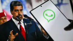Uma pessoa com celular na mão, com símbolo do WhatsApp. Atrás há uma foto de Nicolás Maduro