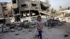 A Palestinian girl walks past a destroyed building following overnight Israeli strikes on Jabalia's south-western district of Nazla, in northern Gaza (16 April 2025)
