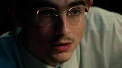 Primer plano de Timothée Chalamet, caracterizado como la estrella del tenis de mesa Mary Reisman, en una escena de Marty Supreme.