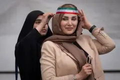 A veiled pro-government supporter wears an Iranian national flag after a ceremony to commemorate civilians and military personnel who were killed during military operations involving the United States and Israel, at the Imam Khomeini Grand Mosque in downtown Tehran, Iran, on May 24, 2026.