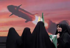 Một nhóm phụ nữ Iran đứng trước màn hình có chiếu hình tên lửa
