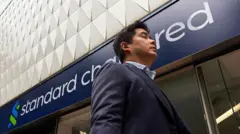 A pedestrian walks past a Standard Chartered bank branch on 17 March, 2026 in Hong Kong.
