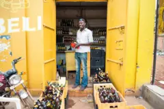 Umugabo w’Umwirabure ariko aramwenyurira imbere y’imangazini icuruza ibinyobwa biborera.
