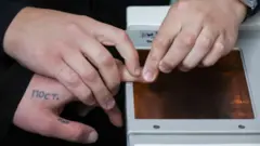 У человека снимают отпечатки пальцев 