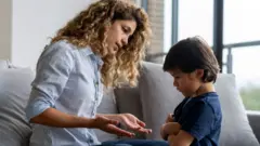 Menino com os braços cruzados e cabeça baixa, recusando-se a negociar com sua mãe