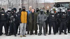 El comandante de la Oficina de Aduanas y Protección Fronteriza de EE.UU. UU., Gregory Bovino (C), se encuentra flanqueado por otros agentes federales durante una protesta contra ICE frente al Edificio Federal Bishop Whipple en Minneapolis, Minnesota, el 15 de enero de 2026. (Foto de Octavio JONES/AFP vía Getty Images)