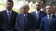 Devlet Bahçeli MHP'nin kurucu genel başkanı Alparslan Türkeş'in kabrini ziyaret ediyor, yanında takım elbiseli kişiler var