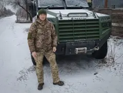 Vitalii Hodniuk uniformado frente a un camión militar en una calle nevada.