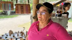 A comerciante María Moreno, de perfil, conversa com a BBC Mundo sobre o impacto econômico deixado pelos visitantes da tumba de Omaira.