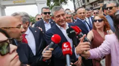 Yeni Parti Genel Başkanı seçilen Özgür Özel arkasındaki kalabalıkla kendisine mikrofon tutan gazetecilere konuşuyor