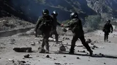 Policiais de choque removem pedras de uma estrada bloqueada por manifestantes rurais em Lipari, departamento de La Paz, Bolívia, em 16 de maio de 2026.