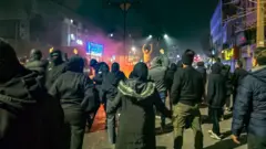 شامگاه ۹ ژانویه معترضان در محله تهرانپارس تهران شبانه در اطراف آتشی در جریان اعتراضات سراسری ایستاده‌اند و شعار می‌دهند.
