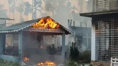 টিনের চাল দেওয়া পাকা একটি ঘরে আগুন জ্বলছে, পারপাশে ধোঁয়া