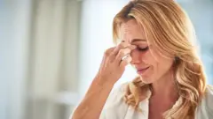 Žena plave kose se drži za glavu