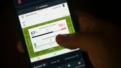 Mão segurando celular com um site de apostas esportivas aberto na tela