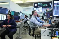 Operadores de bolsa de valores trabalhando em frente às telas de computadores