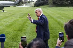 Трамп махає рукою на прощання журналістам, розвертаючись від них у напрямку свого гелікоптера на галявині перед Білим домом