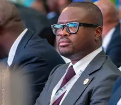 Romuald Wadagni, ministre candidat en costume portant des lunettes et une cravate en train de fixer un objectif hors champ.