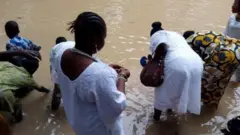 Awọn eeyan to wọ asọ funfun wa ni ojubọ Osun Osogbo, wọn n bu omi inu odo 