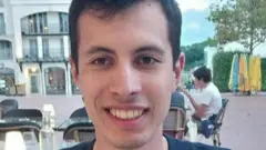 Молодой человек по имени Кантан Деранк сидит в уличном кафе.