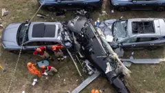 Una vista aérea muestra a bomberos trabajando en el lugar donde se estrelló un helicóptero en el barrio de Recreio dos Bandeirantes, en Río de Janeiro, el 14 de junio de 2026.