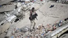 Un voluntario carga a un perro rescatado entre los escombros de un edificio colapsado tras dos terremotos consecutivos en Caraballeda, estado de La Guaira, a unos 40 km al noreste de Caracas, el 25 de junio de 2026.