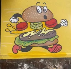 Um hambúrguer com olhinhos e bracinhos em posição de corrida fotografado no Bairro Bonfim, em Belo Horizonte, Minas Gerais