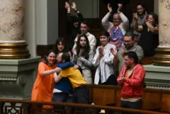 Florencia Salgueiro se abraça a outras pessoas no Congresso durante os aplausos pela aprovação da lei de eutanásia no Uruguai, em 15 de outubro de 2025.