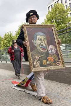El artista Semyon Skrepetsky camina con uno de sus cuadros