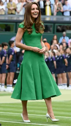 Kate Middleton, princesa de Gales, de vestido verde, andando pela quadra de grama de Wimbledon