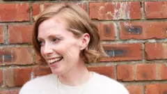 Mulher de cabelo curto sorri.