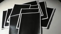 Decenas de páginas copletamente tachadas en negro yacen sobre una mesa.