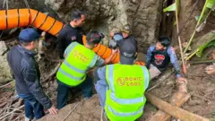 Rescuers trying to fix an orange pump onto one of the cave's entrances