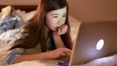 طفلة صغيرة تستخدم جهاز كمبيوتر محمول.
