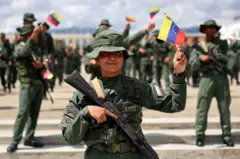 Uma mulher integrante da Força Armada Nacional Bolivariana segura uma pequena bandeira da Venezuela