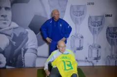 Zagallo está sentado em uma cadeira de rodas e posa em frente a sua estátua de cera inaugurada no Museu da Seleção Brasileira, na sede da Confederação Brasileira de Futebol (CBF), no Rio de Janeiro, em 2022