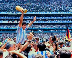 Diego Armando Maradona es sostenido en hombros mientras levanta la Copa del Mundo.