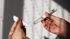 Bir kişi elinde, içinde sıvı olan bir tüpü ve kapağını tutuyor