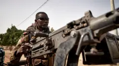 One soldier from di Malian army wey carry machine gun dey for back of truck as dem dey patrol di road between Mopti and Djenne