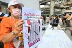 ประชาชนแสดงตัวอย่างบัตรเลือกตั้ง สส.ปาร์ตี้ลิสต์ ที่มีบาร์โค้ดด้านล่าง และตั้งคำถามว่าจะทำให้การเลือกตั้งเป็นโมฆะหรือไม่ ระหว่างร่วมชุมนุมประท้วงการจัดการเลือกตั้งของ กกต. ที่หอศิลปวัฒนธรรมแห่งกรุงเทพฯ เมื่อ 14 ก.พ.