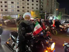 Homens armados em motocicletas agitando bandeiras iranianas no centro de Teerã.