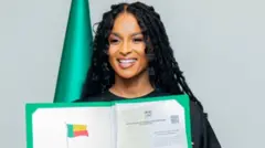 Ciara sorrindo e mostrando certificado, com bandeira atrás