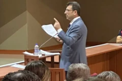 Ekrem İmamoğlu mahkeme salonunda kürsüde ve elinde beyaz bir kağıt var, Tek eli havada ve savunma yaptığı anlaşılıyor