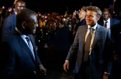 Le président français Emmanuel Macron (à droite) est accueilli par le Premier ministre camerounais Joseph Dion Ngute (à gauche) à son arrivée à l'aéroport international de Nsimalen à Yaoundé, le 25 juillet 2022.