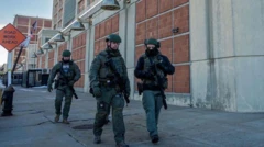 ব্রুকলিনের এমডিসির সামনে কয়েকজন নিরাপত্তা কর্মী হেঁটে যাচ্ছেন