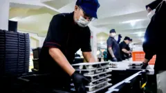 Relawan atau pekerja di dapur makan bergizi gratis di Lapas Sukamiskin sedang menyiapkan makanan dalam ompreng yang akan dibagikan kepada pelajar penerima manfaat.