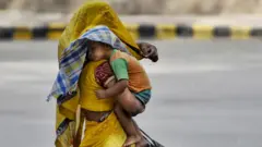 उन्हात मुलाला कडेवर घेऊन चालणारी आई
