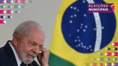 O presidente Luiz Inácio Lula da Silva posicionando um foneslot real downloadouvido com uma bandeira do Brasil ao fundo