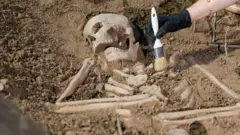 Um esqueleto humano sendo desenterrado por pesquisadores.