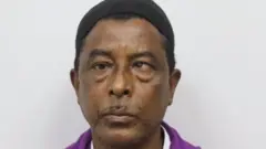 Nurul Amin Shah Alam en la foto con un traje violeta. 